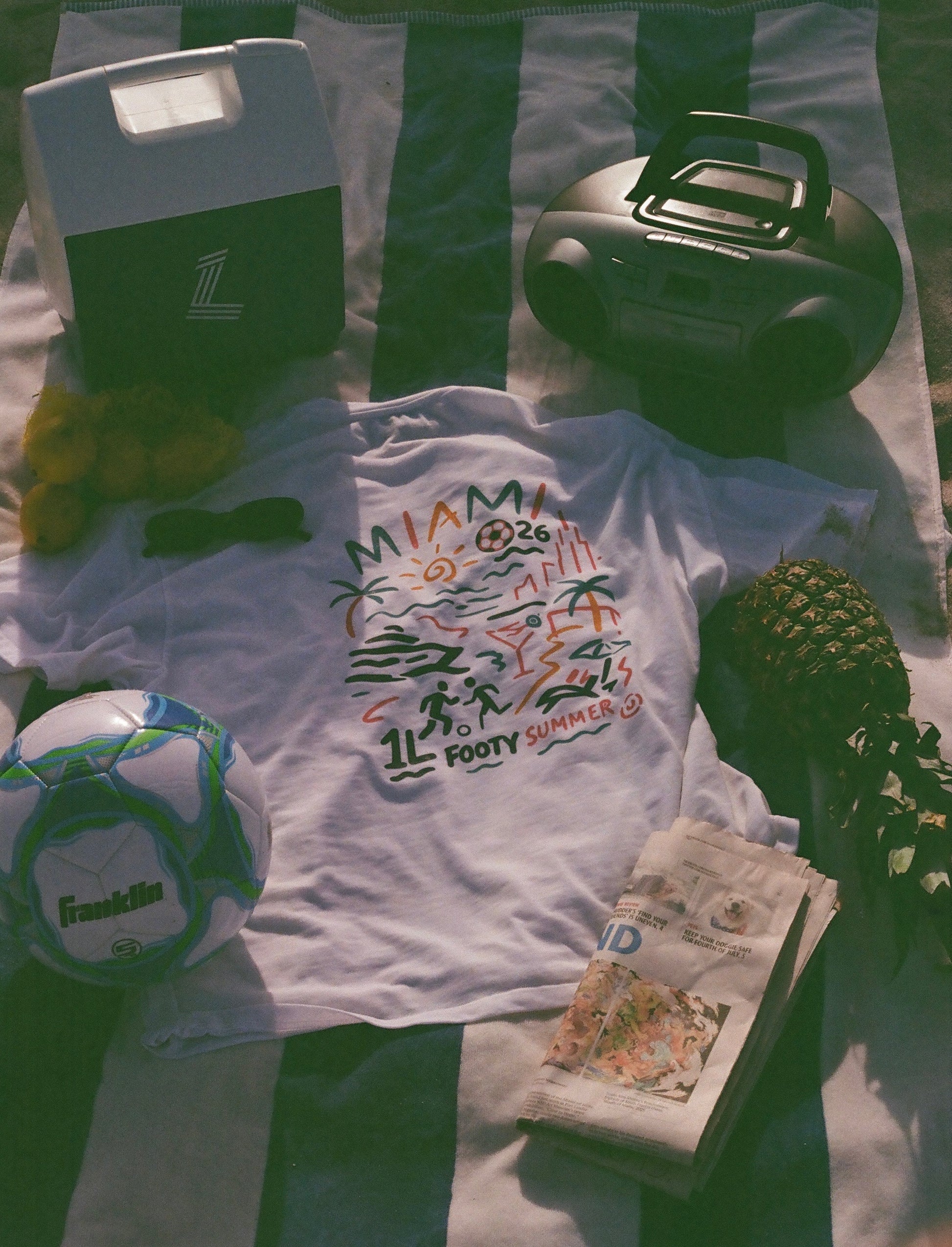 White Endless Summer Tee displayed on a beach towel with a soccer ball, radio and summer accessories