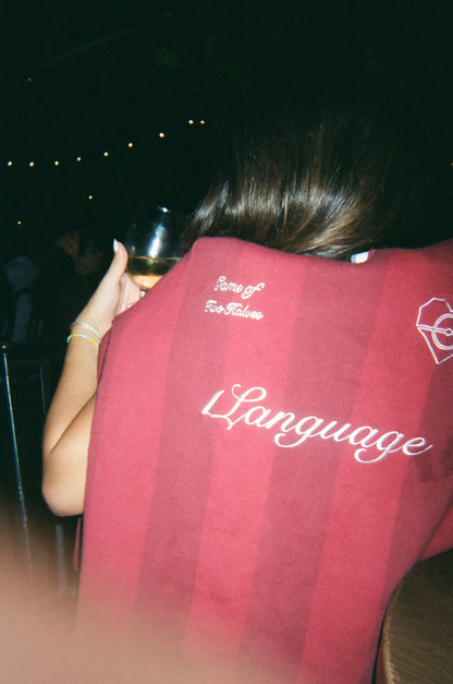 Close-up of the Red Rock Polo showing embroidered 1Language lettering, Game of Two Halves text and heart-shaped soccer-pitch badge