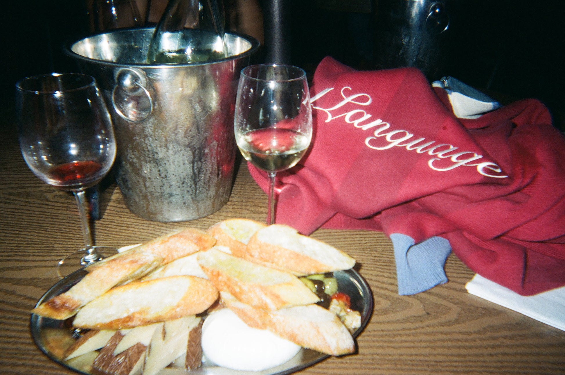 Red 1Language Red Rock knit polo styled beside wine glasses and a shared dinner table