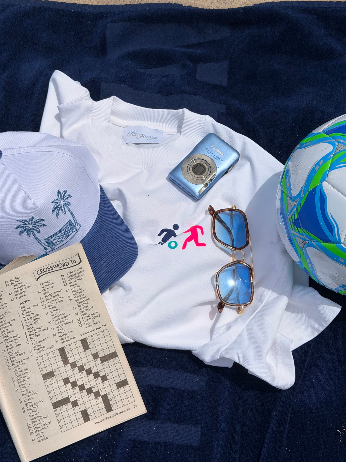 1Language Endless Summer Tee and hat styled with a soccer ball, sunglasses and camera on a beach towel