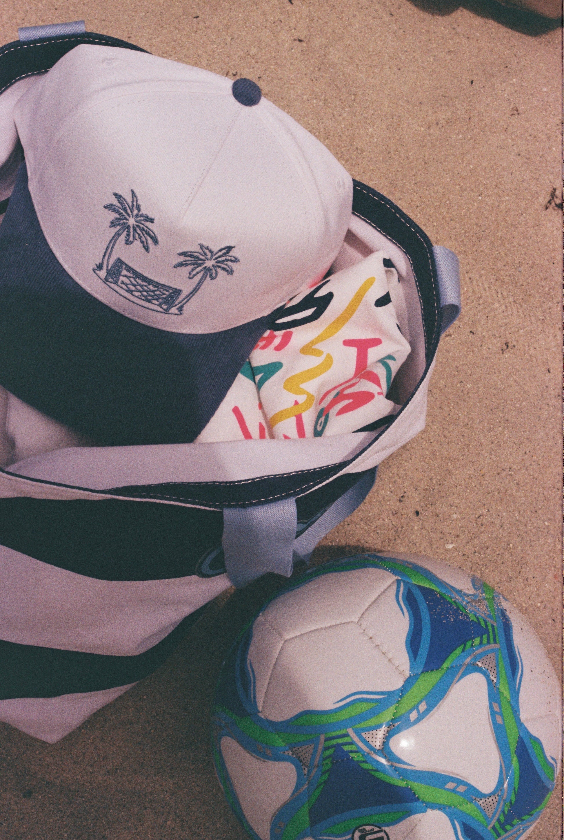 Endless Summer Hat displayed with the matching graphic tee, beach bag and soccer ball
